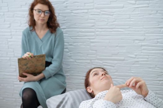 A middle-aged woman lies on a couch and talks to a psychologist