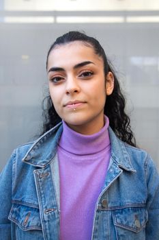 Portrait of young teenage girl looking at camera wearing purple turtleneck and denim jacket. Vertical image. Lifestyle and gen z concept.