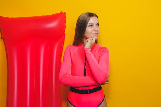 Young woman slim body pink one piece swimsuit on pink air mattress isolated on bright yellow color studio background summer hotel swimming pool sea vacation sun tanning concept. Place for text