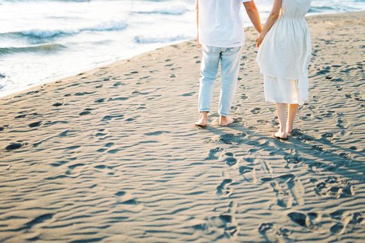 Man and woman stand on the sand holding hands. Cropped. High quality photo