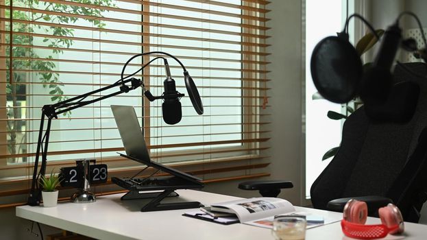Home studio with professional condenser microphone, laptop and headphone. Entertainment, podcasts and technology concept.