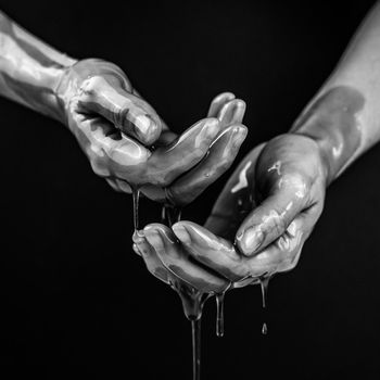 Women's hands in a viscous liquid similar to blood. Black and white photo