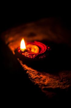 Close-up shot of burning Diva or divida or Diya or oil lamp isolated in dark.