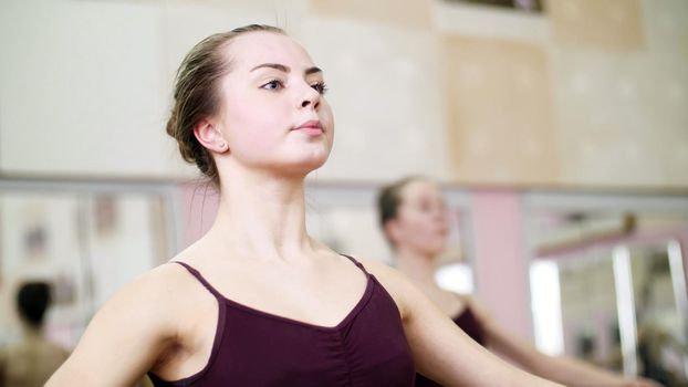 in dancing hall, Young ballerina in purple leotard performs a certain ballet exercise, first position of hands,. High quality photo
