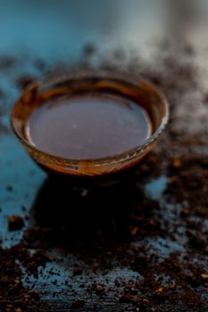 A bowl full of chocolate milk on a black wooden surface with some raw cocoa powder sprinkled around it.