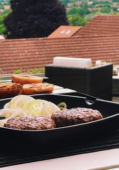 Cooking minced beef burger on cast iron grill skillet outdoors, red meat on frying pan, grilling food in the garden, English countryside living concept