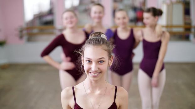 portrait of a young girl ballet dancer in a lilac ballet leotard, smiling, sending an air kiss, gracefully performing a ballet figure. High quality photo