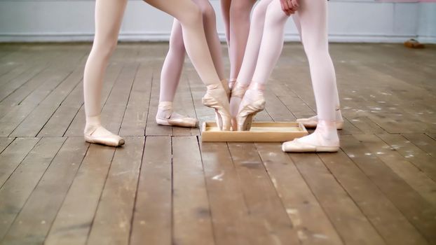 close-up, the feet of young dancers, the girls lower the tips of the pointe shoes into a box with special powder. High quality photo