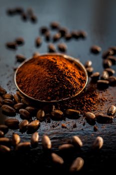 Shot of raw coffee beans and powder on a black surface.