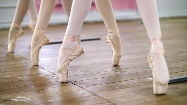 in ballet hall, Young ballerinas perform pas echappe in pointe shoes, goes up on toes, close-up. High quality photo