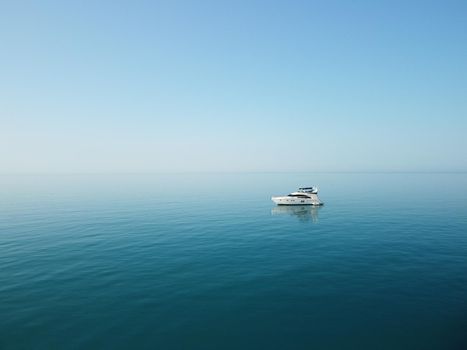 Aerial boat race. Luxury cruise trip. View from above of white boat on deep blue water. Aerial view of rich yacht sailing sea. Motor boat racing wave. Summer journey on luxury ship