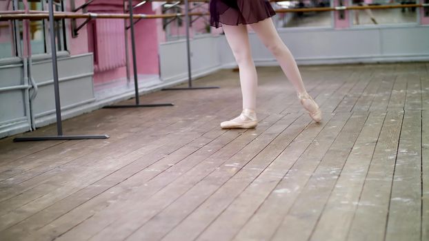 in dancing hall, Young ballerina in purple leotard performs tour jete en dedans, She is moving through the ballet class elegantly,. High quality photo