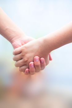 Hand of female child holding the hand of matured man, Shot with blurred background. Concept of Father’s day. Men helping the female hand to overcome conquer obstacles and fears. Vertical shot.