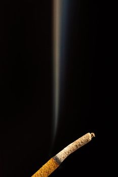 Close-up of smoking stick of incense isolated on a black background.