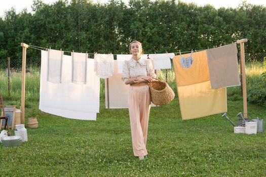 Laundry day. A woman hangs linen and towels on a tree in the courtyard of a village house. Summer cottage concept.