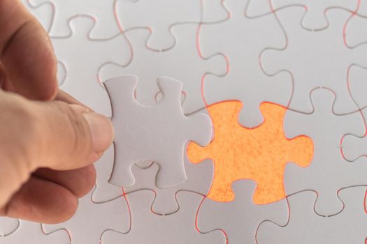 A hand hold the missing piece of white jigsaw puzzle