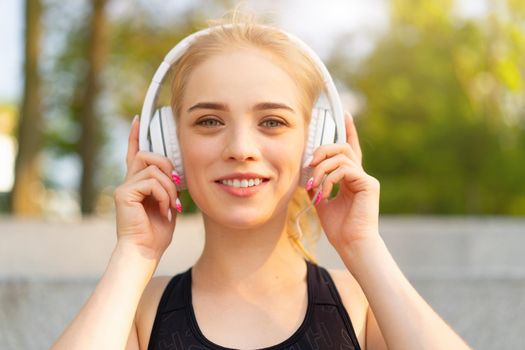 Sport and Fitness Young Adult Caucasian Woman Resting after morning Workout Outdoor Summer Park Athletic Female Take a Break listen Music Headphones