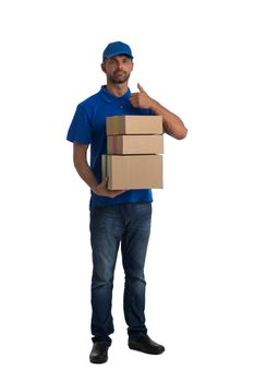 Smiling young post employee with parcels giving thumb up isolated on white background