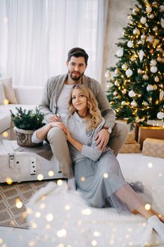 A happy couple in love - a man and a woman. A family in a bright New Year's interior with a Christmas tree.