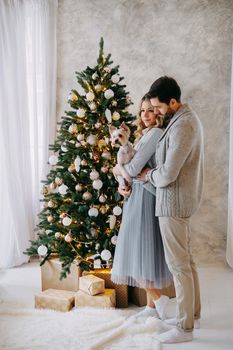 A happy couple in love - a man and a woman. A family in a bright New Year's interior with a Christmas tree.