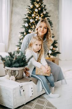 Happy family: mother and daughter. Family in a bright New Year's interior with a Christmas tree.