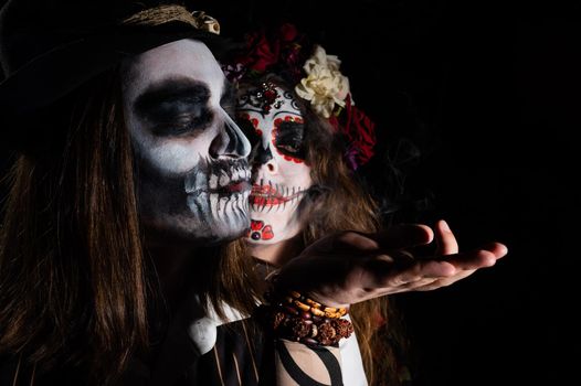 Woman in santa muerte costume and man in skeleton bodypainting for halloween