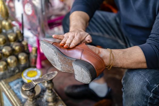 Ancient method of shoe cleaning with help of shoe polish. Man cleans shoes on street, close up.