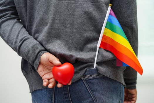 Asian woman holding red hert with rainbow flag, LGBT symbol rights and gender equality, LGBT Pride Month in June.