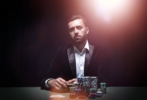 Young man sitting at the poker table with his chips and cards in front of him