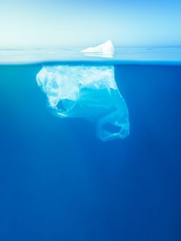 plastic waste underwater, a plastic bag at the Mediterranean sea in the blue water surface like an iceberg, environmental problem. Copy space for text, vertical photo