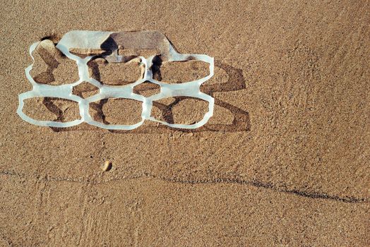 background of a plastic rings lies on the sand of the beach and pollutes the sea and the marine life, concept of pollution control of the oceans by plastic, copy space for text