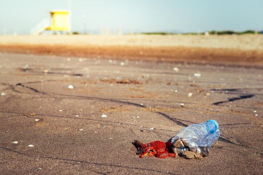 plastic bottle and trash lies on the sand of the beach and pollutes the sea and the marine life, concept of pollution control of the oceans by plastic