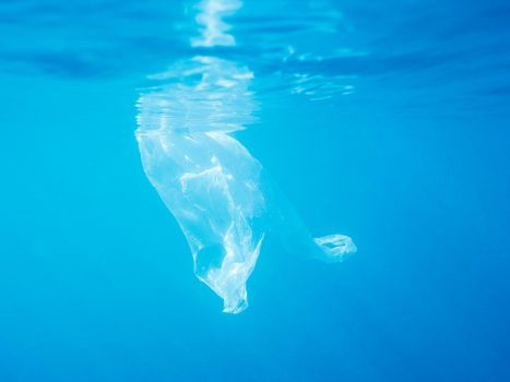 plastic waste underwater, a plastic bag in the Mediterranean sea near of blue water surface, environmental problem