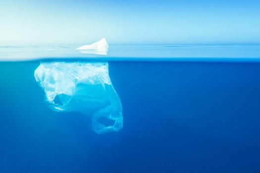 plastic waste underwater, a plastic bag at the Mediterranean sea in the blue water surface like an iceberg, environmental problem. Copy space for text