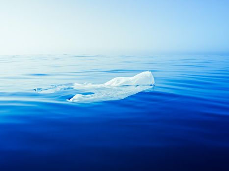 plastic waste at the ocean, a plastic bag in the Mediterranean sea floating at the blue water surface, environmental problem with plastics pollution, copy space for text
