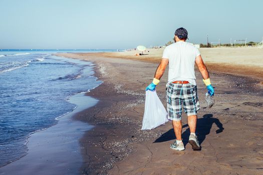 volunteer collecting waste that pollute the ocean in plastic bag, people helping to keep nature clean and picking up the plastics from sea, volunteer campaign to cleaning on the beach