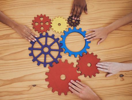 Hands, gears and collaboration with a team of people working with cogs and equipment on a table in the office. Teamwork, synergy and planning with a business group meeting to talk company strategy.