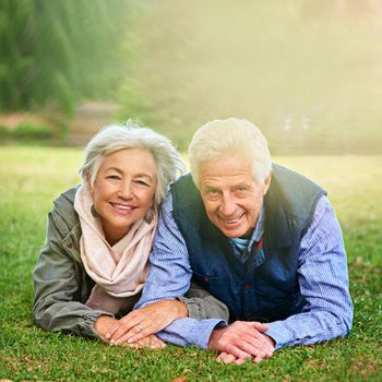 Living the retirement dream. Portrait of a happy senior couple lying down on the grass together in the park