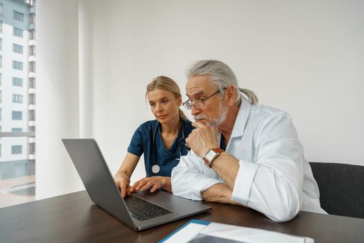 Two doctor colleagues discussing patient diagnosis sitting in office of medicine clinic