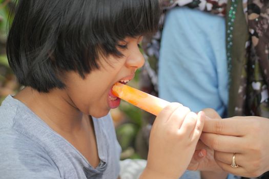 child girl eating orange ice cream ,