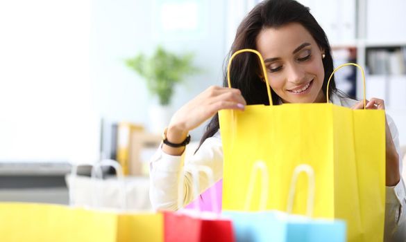 Beautiful woman is amazed to see gift in shopping bag. Concept of shopping and gifts