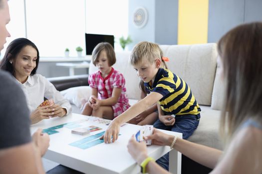 Parents and children play board game together at table. Games for whole family at home