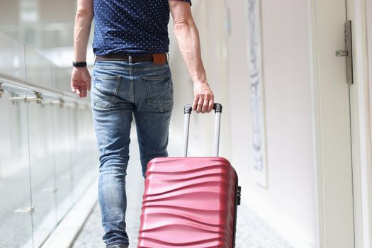 Male tourist pulls suitcase moving to luxury hotel. Booking and check-in at the hotel
