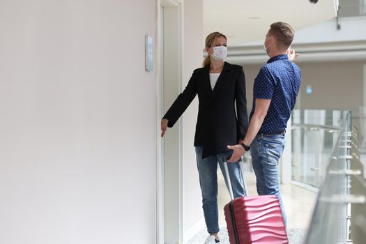 Two tourists observe sanitary rules during pandemic and check into room in hotel room. Travel health safety concept