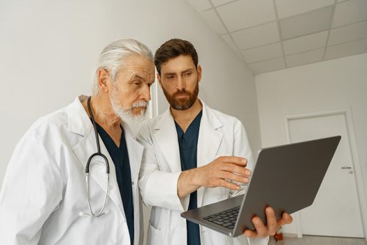 Two doctor colleagues discussing patient diagnosis stand in medicine clinic hall