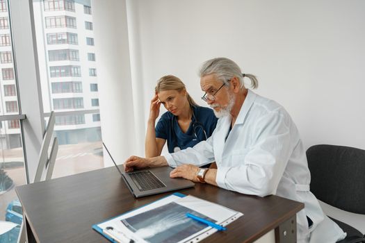 Two doctor colleagues discussing patient diagnosis sitting in office of medicine clinic