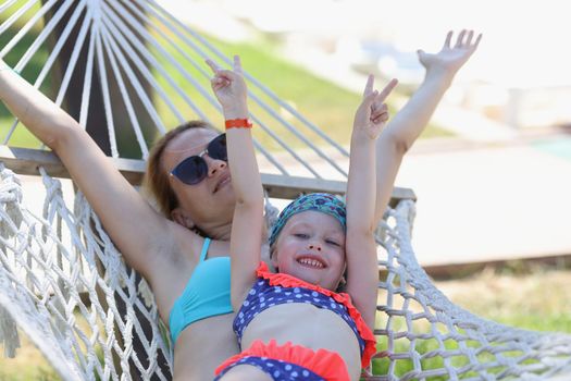 Loving family mom and daughter spend time together in summer hammock. Family happy joyful vacation in summer garden
