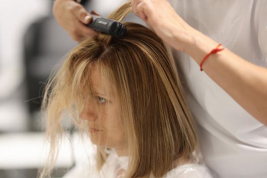 Pulling strands of hair with professional iron care. Keratin straightening and hair restoration