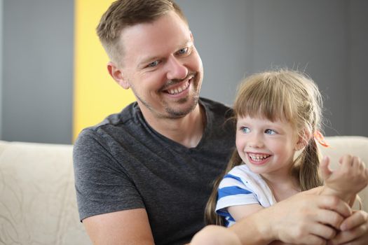 Happy dad holding cute cheerful daughter laughing and having good time together. Loving father and smiling little girl hugging and caring dad