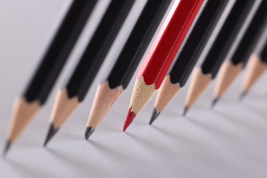 Red pencil separating row of black pencils. Business concept for leadership or thinking differently